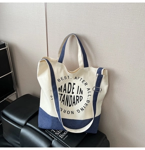 Détail du cabas en toile avec bandoulière réglable et base bleue sur tabouret en cuir