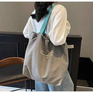 Detail of grey canvas tote bag with blue straps and Dream Together Remember Love text
