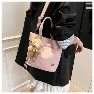 Pink canvas tote bag with bear charm and GO!! 25!! text shown on model shoulder