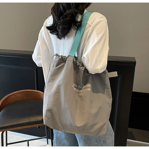 Detail of large capacity tote bag with drawstring closure and printed lettering
