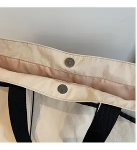 Macro detail of tote bag with metallic magnetic buckles and textured nylon fabric