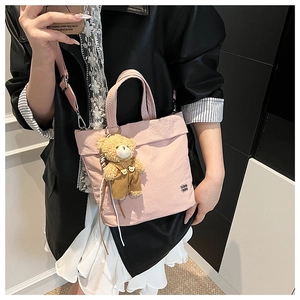 Pink fabric tote bag detail with cute bear plush charm and adjustable shoulder strap