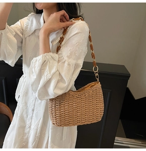 Detail of straw shoulder bag featuring amber tortoiseshell chain and gold metal links