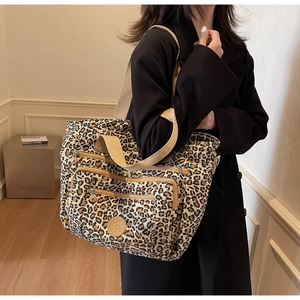 Detail of leopard print tote bag showing multi-zipper pockets and fabric texture
