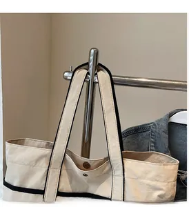 Detail of canvas tote bag showing strong metal magnetic buckle and wide shoulder strap