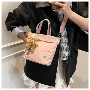 Pink crossbody tote bag with cute bear charm and adjustable wide shoulder strap detail