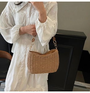 Detailed shot of straw woven bag featuring amber resin chain and gold hardware
