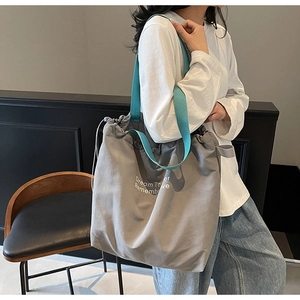 Detail of grey canvas drawstring tote bag with sky blue shoulder straps and text print