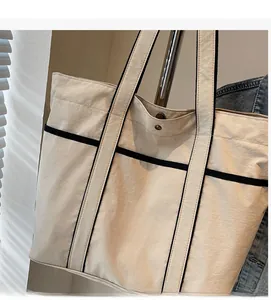 Detail of beige tote bag showing internal metal magnetic closure and contrast piping