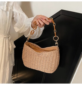 Detail of straw shoulder bag with amber resin chain handle and golden metal rings