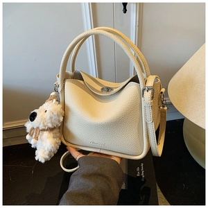Détail du sac à main en cuir grainé crème avec fermoir rotatif et breloque en peluche