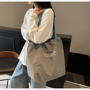 Detail of grey canvas tote bag with Dream Together Remember Love text and blue strap