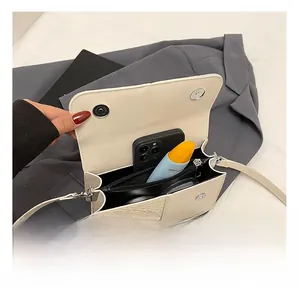 Détail de l'intérieur d'un sac bandoulière blanc cassé montrant le rangement et la poche