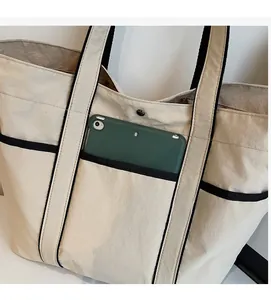 Detail of minimalist tote bag showing front pocket storage and magnetic snap closure