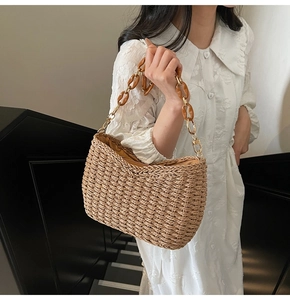 Detail of hand-woven straw shoulder bag with amber acrylic chain and metal buckle