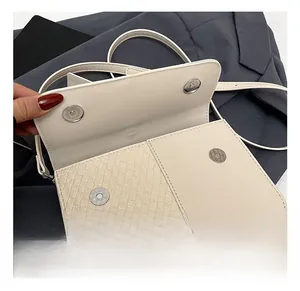 Détail de la texture en cuir beige avec empiècements tissés et fermoir magnétique