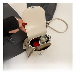 Detail showing inner capacity of creamy white leather crossbody bag with phone and lipstick