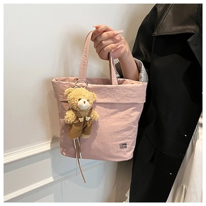 Detail of pink pleated canvas tote bag featuring a cute brown bear doll pendant
