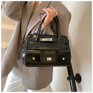 Détail du sac en cuir verni noir avec fermoir rotatif argenté et deux poches avant