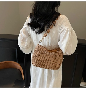 Detail of straw woven shoulder bag with amber resin chain strap on a white dress