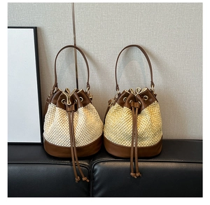 Detail of woven straw bucket bag with brown leather trim and drawstring closure