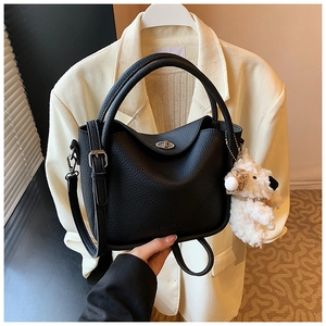 Détails d'un sac à main noir en cuir grainé avec fermoir argenté et breloque chien