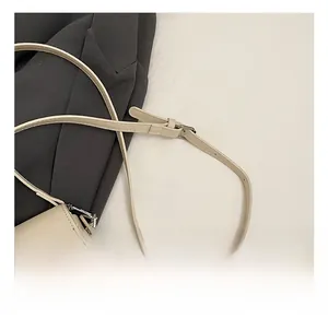 Detail of adjustable beige leather shoulder strap with silver buckle on a handbag