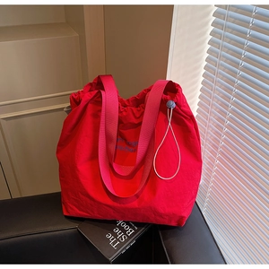 Detail of red nylon tote bag with pink webbing handles and drawstring closure feature