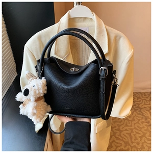 Détail du sac à main noir texture litchi avec fermoir argenté et breloque chien peluche