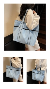 Detail view of large light blue canvas tote bag with black contrast trim and side pockets