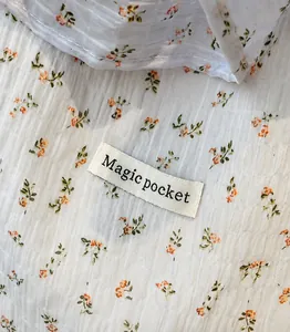 Detail of smocked floral fabric with orange flowers and Magic Pocket brand label