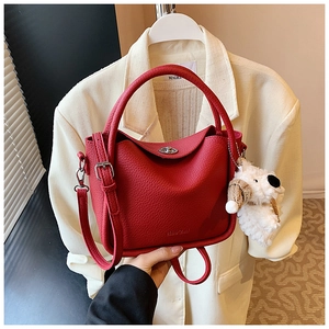 Détail d'un sac à main rouge en cuir grainé avec fermoir argenté et bijou de sac