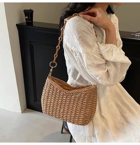 Detail of hand-woven straw hobo bag with unique brown leather and gold ring chain strap