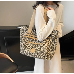 Detail of leopard print tote bag with multiple zipper pockets and wide nylon strap