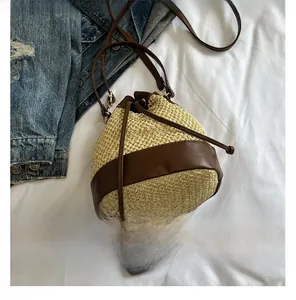 Detail view of contrast color straw bucket bag with drawstring and leather trim