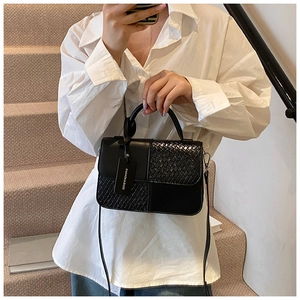 Détail du sac bandoulière noir avec mélange de textures en similicuir lisse et tressé