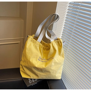 Detail of yellow canvas tote bag with drawstring closure on a black leather chair