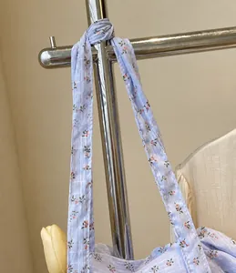 Detail of light blue floral cotton strap with red prints and textured woven fabric