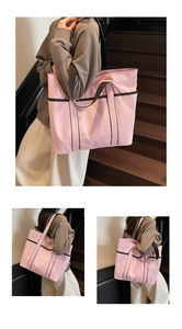 Detail of pink nylon tote bag with contrasting black webbing handles and soft texture