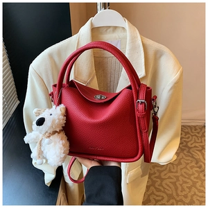 Détail du sac rouge grainé avec fermoir rotatif argenté et breloque ours en peluche