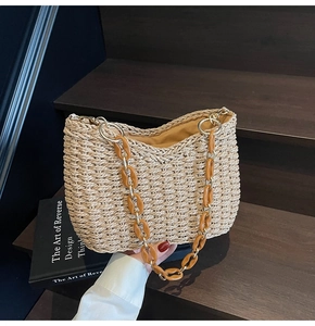 Detail of straw woven bag featuring a vintage brown chain and golden metal ring accents