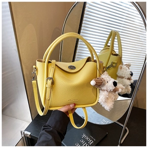 Détail du sac à main jaune avec fermoir tournant en métal et breloque chiot adorable