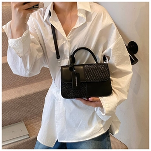 Détail du sac bandoulière noir mêlant cuir lisse et texture tressée avec une bandoulière