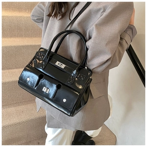 Détail du sac en cuir verni noir avec verrous argentés et poches multifonctions