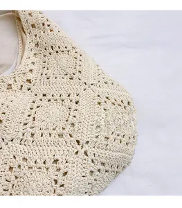 Gros plan du sac à main crocheté beige montrant la texture ajourée et le motif en coton