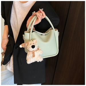 Détail d'un sac à main vert menthe en cuir grainé avec un charmant pendentif ours en peluche