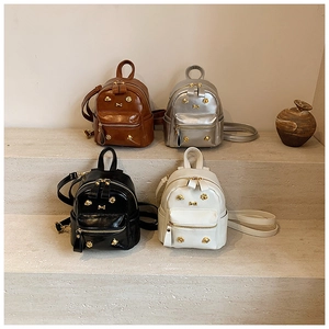 Mini backpacks in brown, silver, black and white displayed on a grey stone staircase