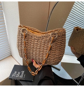 Close-up of straw woven tote with golden metal ring and brown acrylic chain shoulder strap