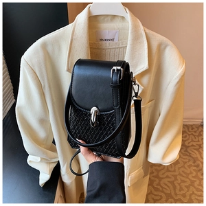 Close-up of black crossbody bag with mixed textures and woven details held by a model