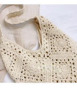 Gros plan d'un sac à bandoulière au crochet beige avec motif floral et sangle tissée